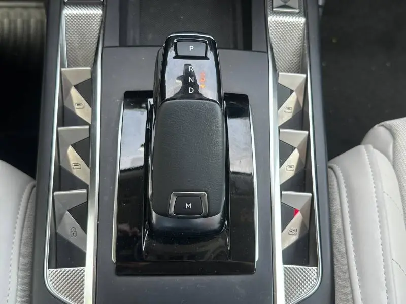 Gros plan sur la console centrale de la DS3 2024, montrant le levier de vitesse automatique entouré de boutons triangulaires argentés.