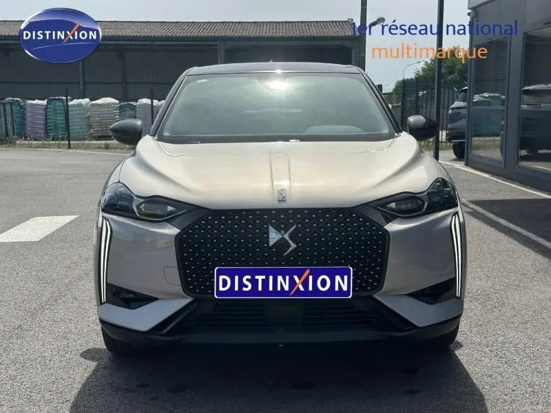 Vue frontale d'une DS3 2024 Cristal Pearl avec toit noir, mettant en valeur sa calandre noire et ses feux LED verticaux.