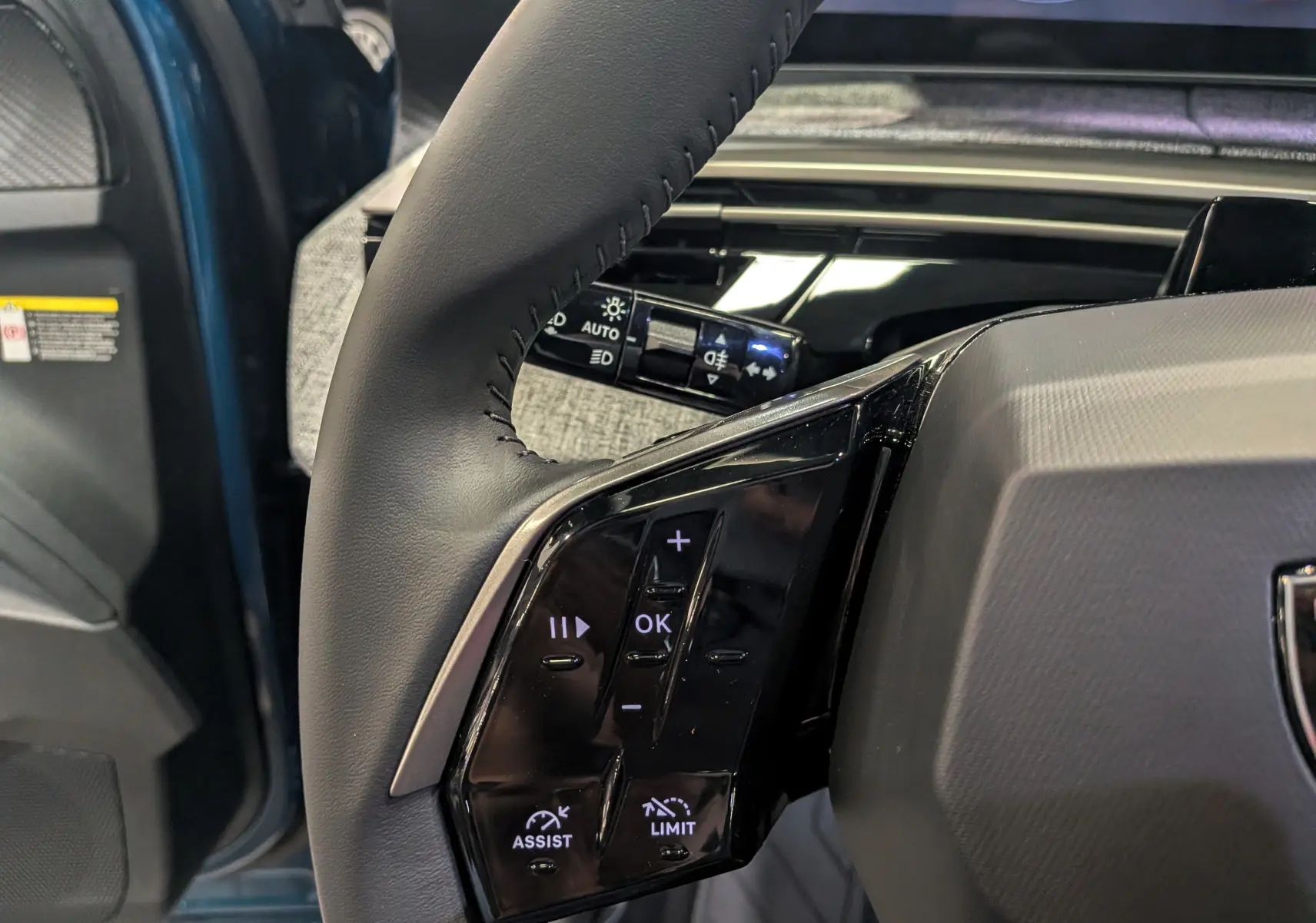 Gros plan sur les commandes au volant côté gauche du Peugeot 3008 Hybrid 145 CH e-DCS6 Allure Bleu Obsession, intérieur moderne.