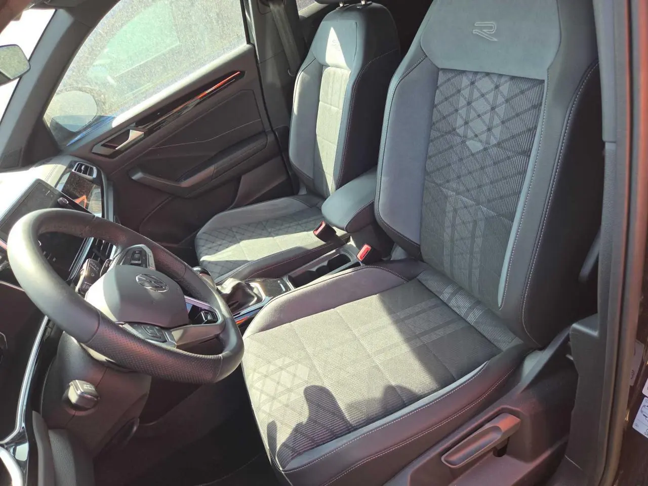 Intérieur avant du Volkswagen T-Roc noir métal 2025, sièges R-Line en tissu et microfleece avec logo brodé.