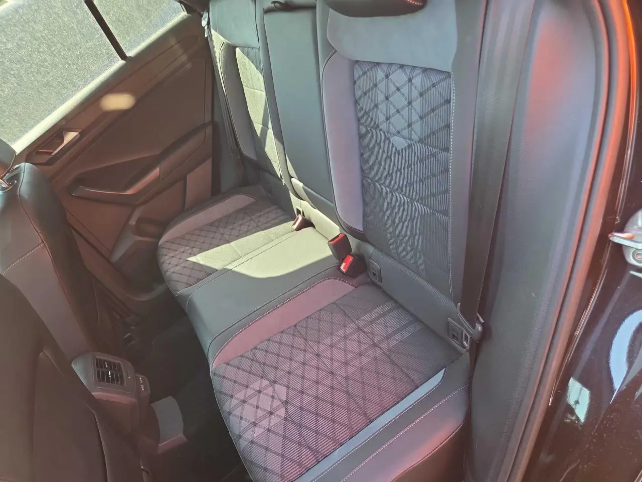 Vue intérieure côté droit de la banquette arrière du Volkswagen T-Roc noir métal avec sellerie tissu et surpiqûres grises.