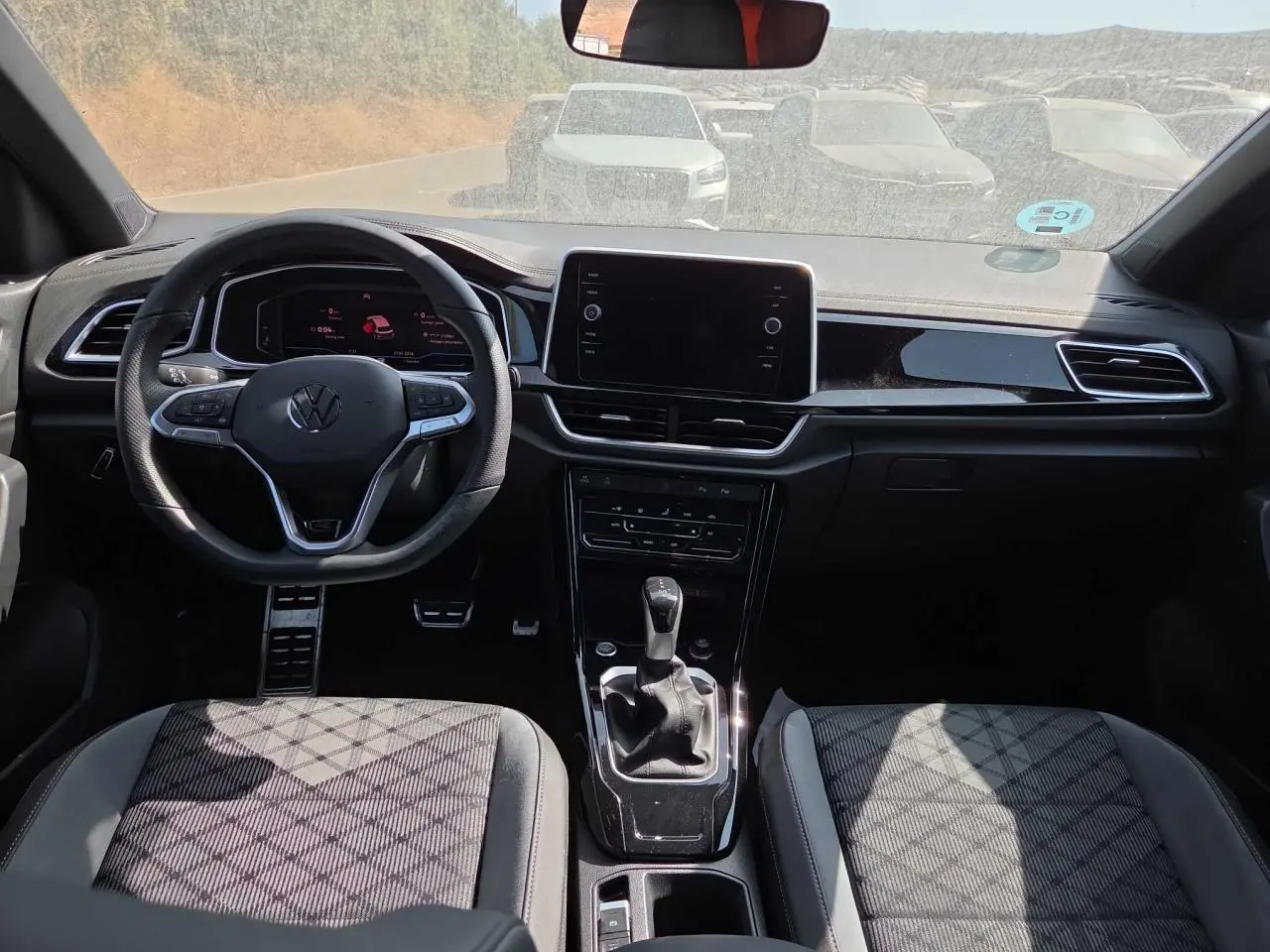Vue intérieure avant du Volkswagen T-Roc 2025 noir métal, avec tableau de bord digital et volant multifonction R-Line.