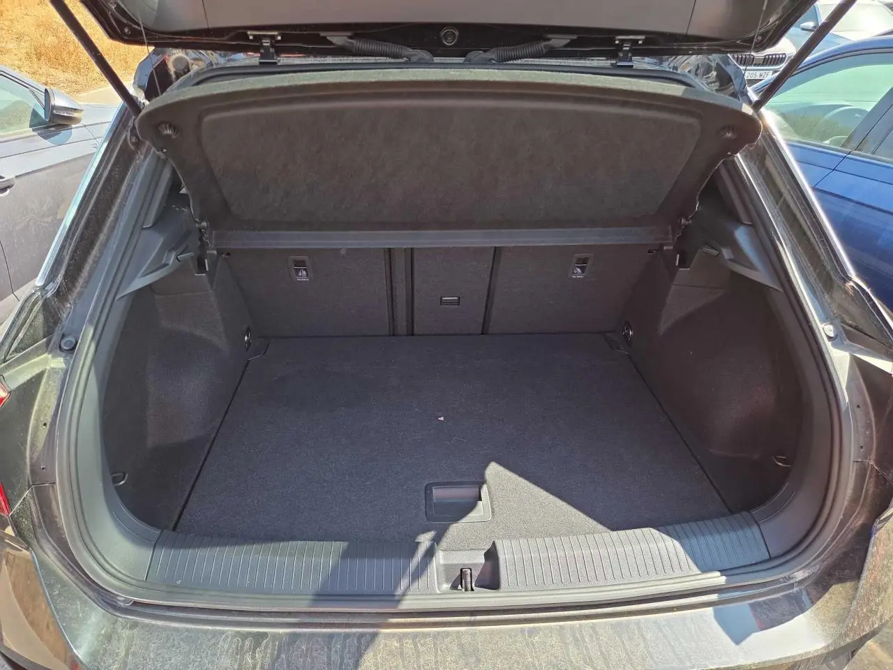 Coffre ouvert du Volkswagen T-Roc noir métal 2025, vue arrière montrant l’espace de chargement vide et propre.