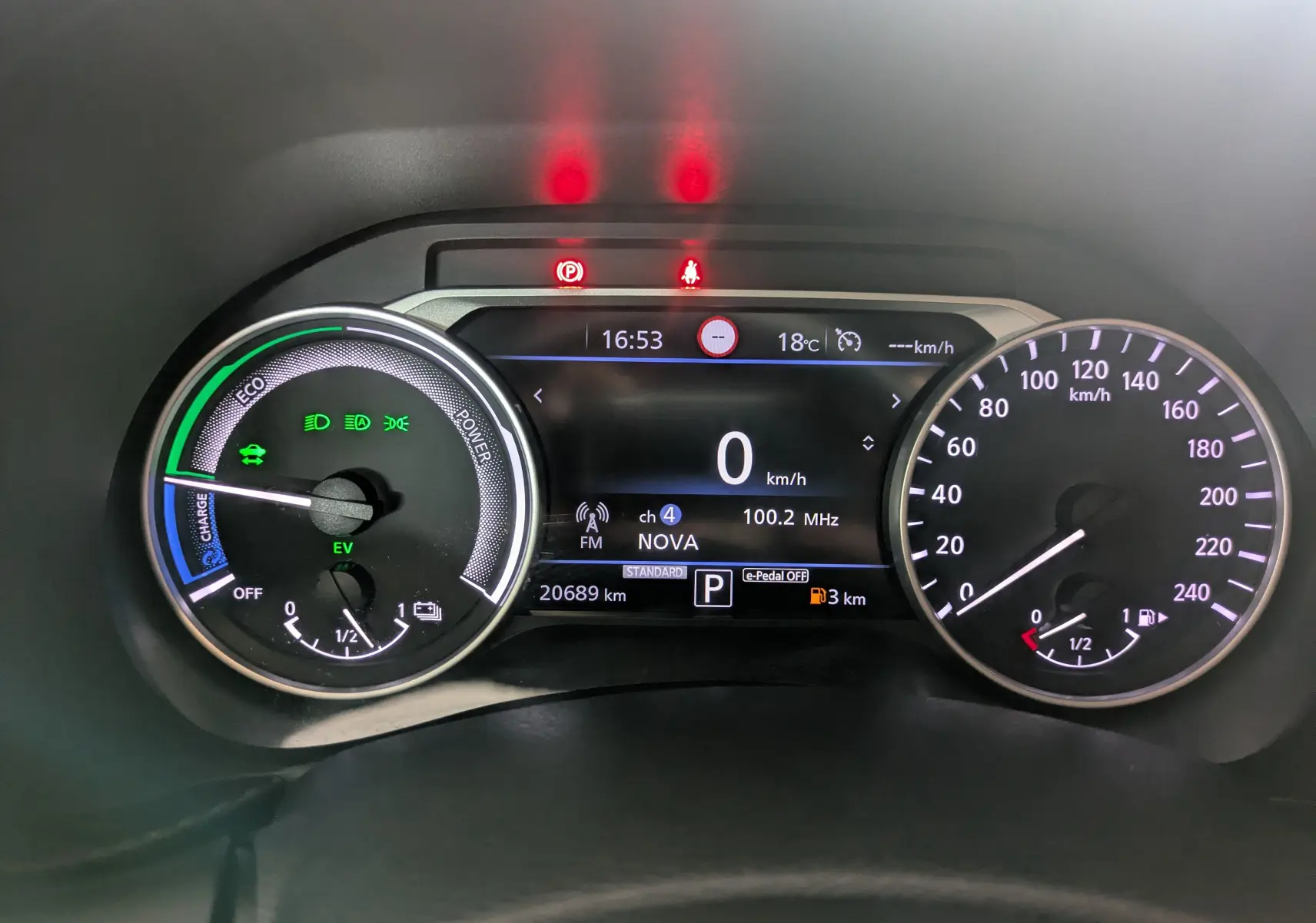 Tableau de bord numérique du Nissan Juke 2024 hybride, affichant vitesse à 0 km/h et indicateurs de charge et carburant.