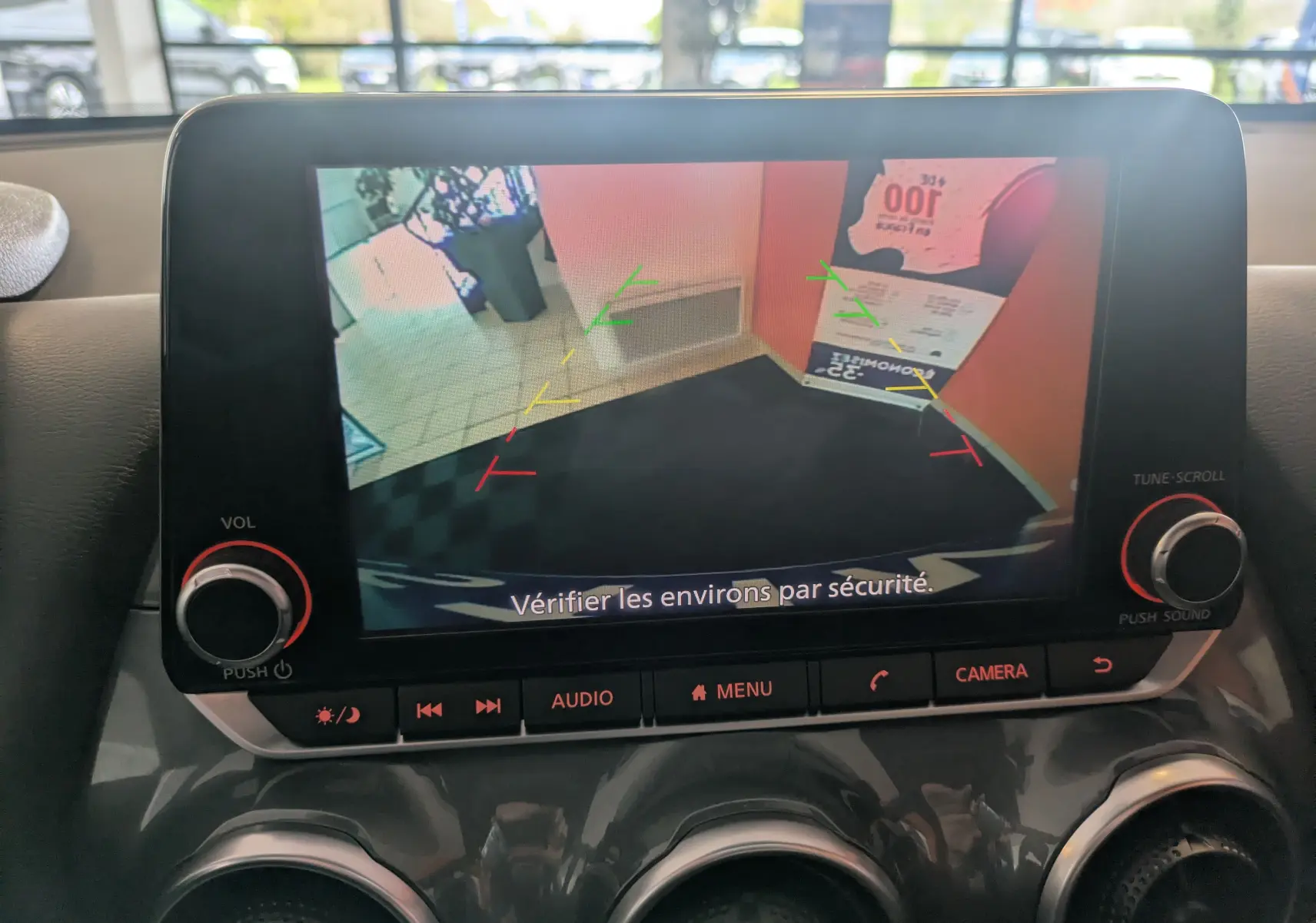 Écran central du Nissan Juke 2024 montrant la caméra de recul avec repères colorés et message de sécurité.
