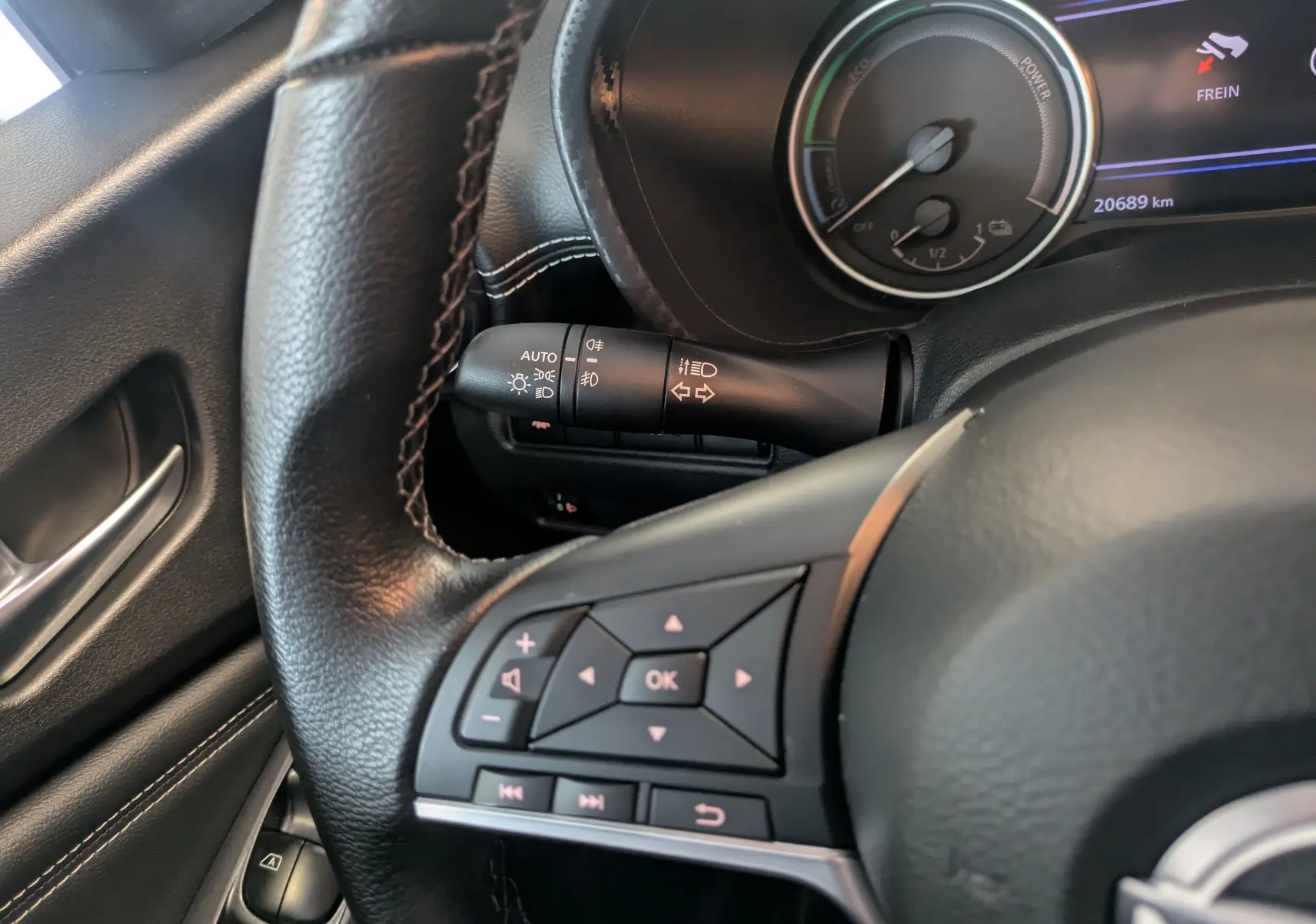 Gros plan sur le volant et les commandes à gauche du tableau de bord d'un Nissan Juke 2024 gris squale métal hybride.