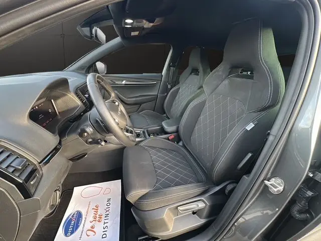 Vue intérieure côté conducteur du Skoda Karoq gris graphite 2025, sièges sport noirs avec surpiqûres et tableau de bord digital.