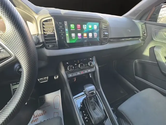 Vue intérieure côté conducteur du tableau de bord et console centrale du Skoda Karoq gris graphite avec écran tactile et levier de vitesse DSG7.