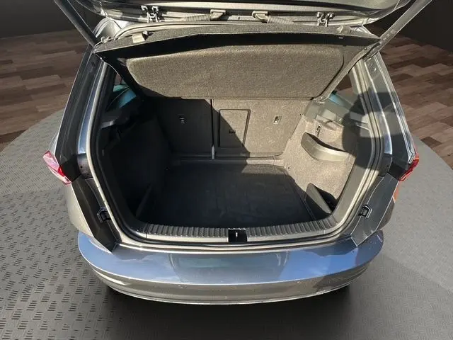 Coffre ouvert vu de l'arrière d'un Skoda Karoq gris graphite 2025, montrant un espace de chargement vide et propre.