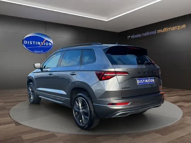 Vue 3/4 arrière droite d'un Skoda Karoq gris graphite avec jantes noires et feux arrière LED en showroom.