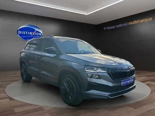 Vue 3/4 avant d'un Skoda Karoq gris graphite 2025 avec jantes noires et calandre marquée SPORTLINE.
