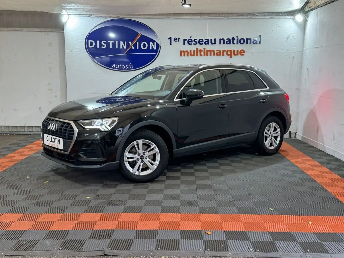Audi Q3 noir vue 3/4 avant droit en intérieur avec jantes argentées et logo Distinxion en arrière-plan