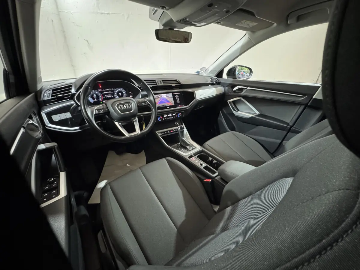 Intérieur noir de l'Audi Q3 35 TFSI 2022 vu côté conducteur, avec tableau de bord digital et écran central tactile.