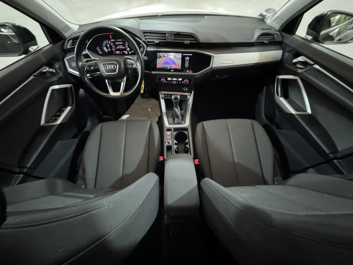 Intérieur noir de l'Audi Q3 2022, vue avant du poste de conduite avec écran tactile et volant multifonctions cuir.