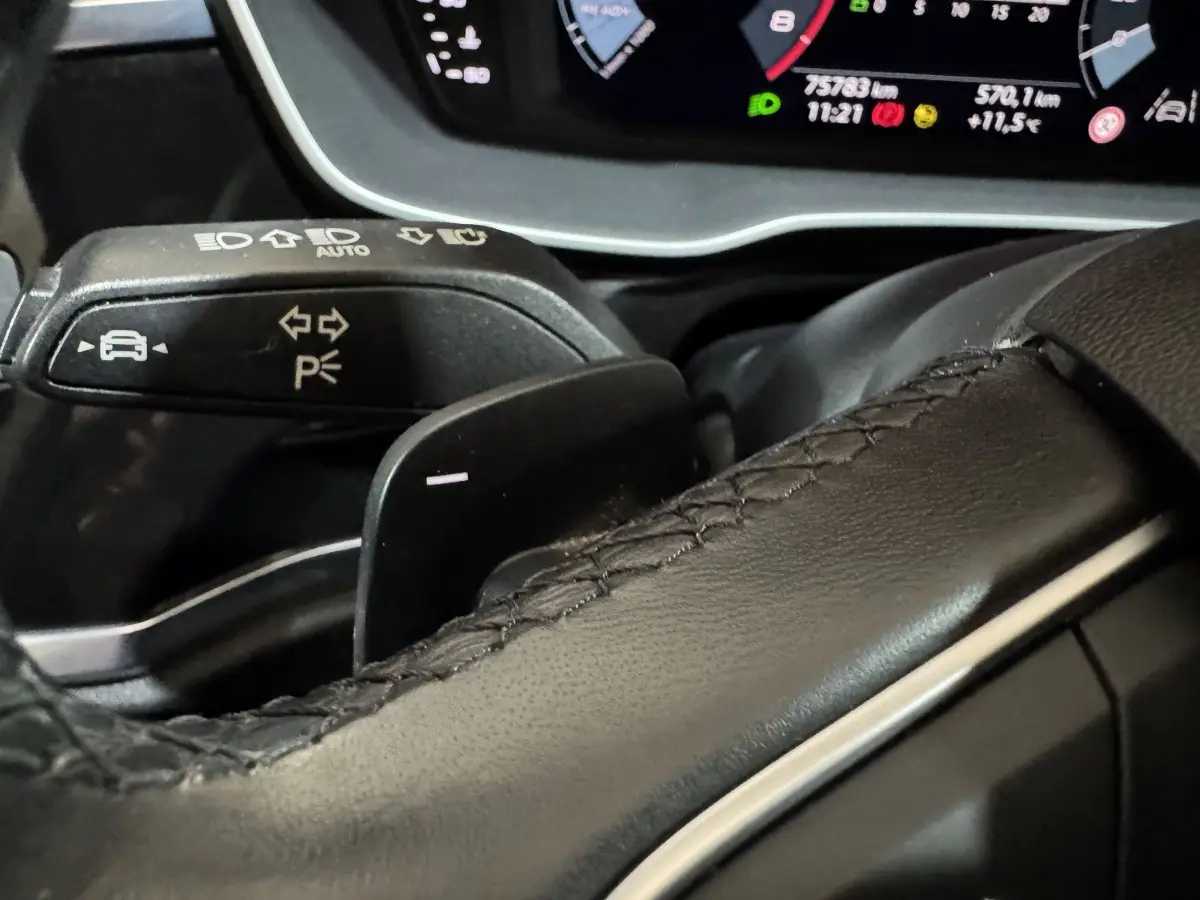 Gros plan sur le volant cuir noir et la commande de clignotants du tableau de bord numérique de l'Audi Q3 35 TFSI 2022.