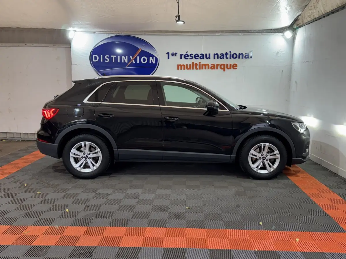 Audi Q3 noir vue de profil côté gauche dans un garage avec logo Distinxion en arrière-plan.