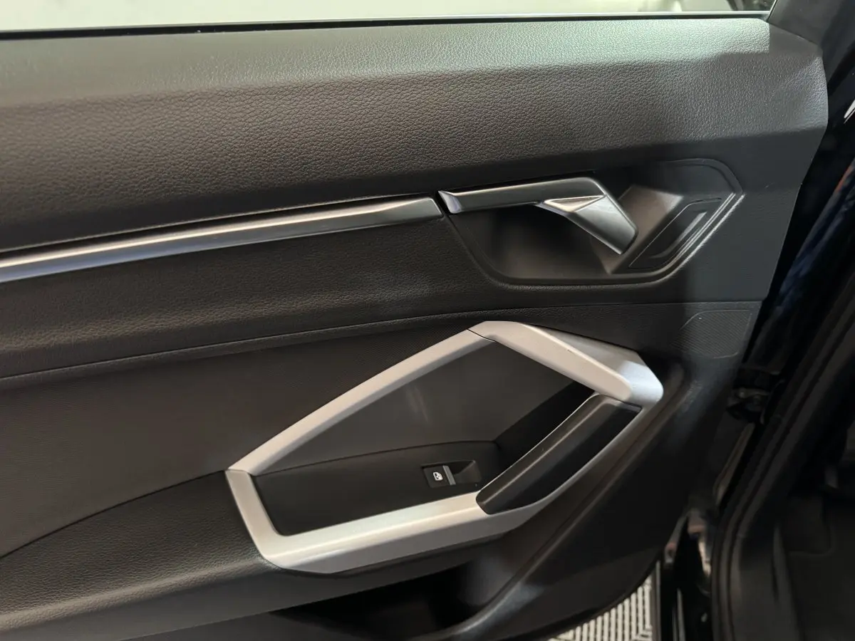 Gros plan sur la porte côté conducteur noire de l'Audi Q3 35 TFSI 2022 avec poignée argentée et bouton de verrouillage.