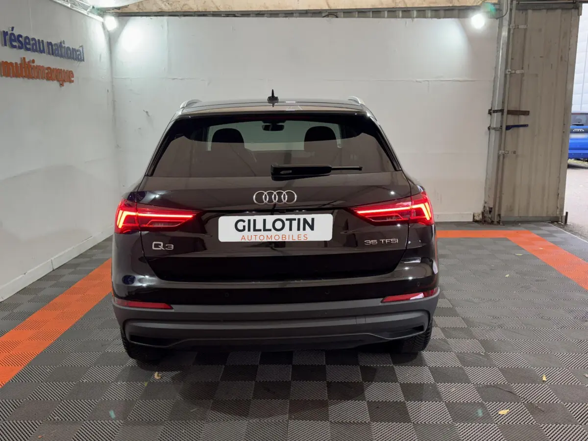 Vue arrière d'un Audi Q3 noir 35 TFSI avec feux LED allumés dans un garage fermé.