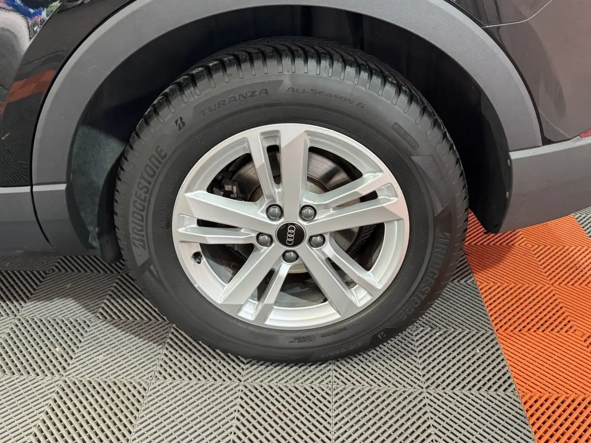 Gros plan sur la roue arrière droite avec jante argentée et pneu Bridgestone du SUV Audi Q3 noir.