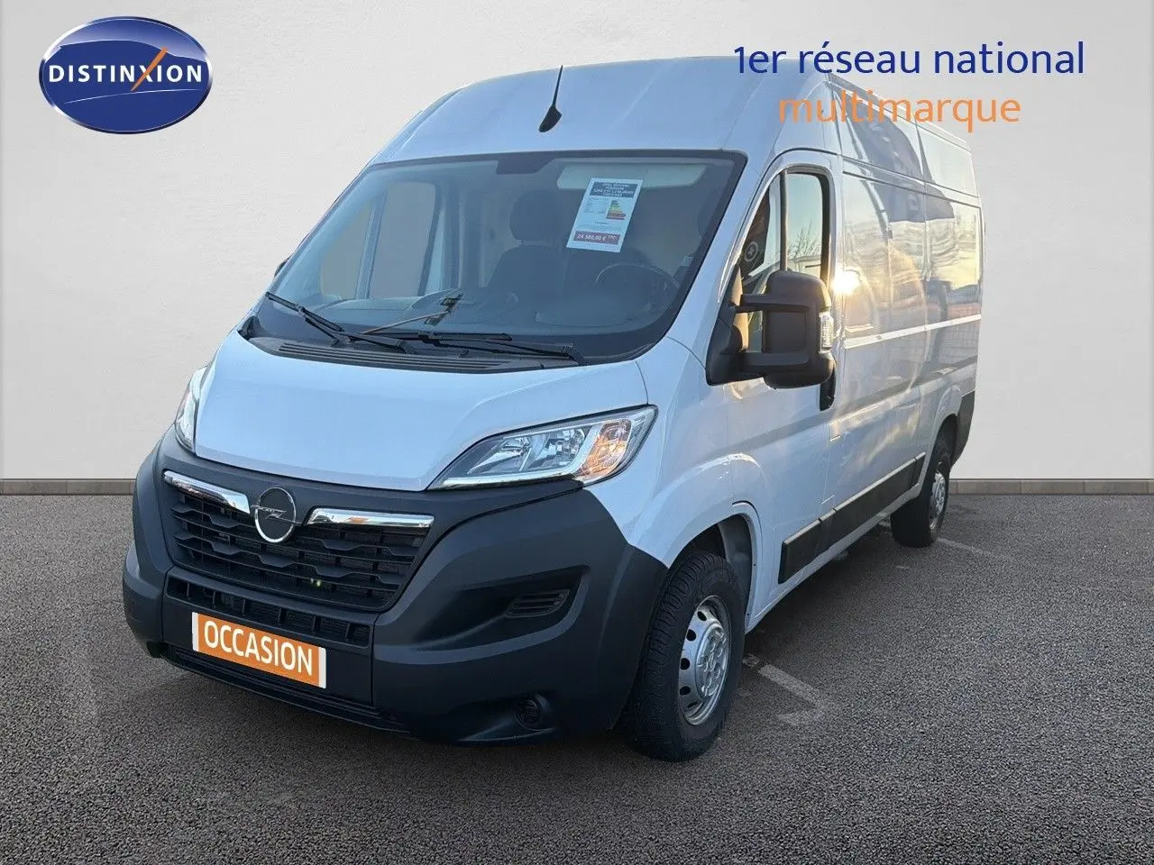Fourgon Opel Movano blanc icy vu en 3/4 avant droit avec calandre noire et plaque "OCCASION" orange.