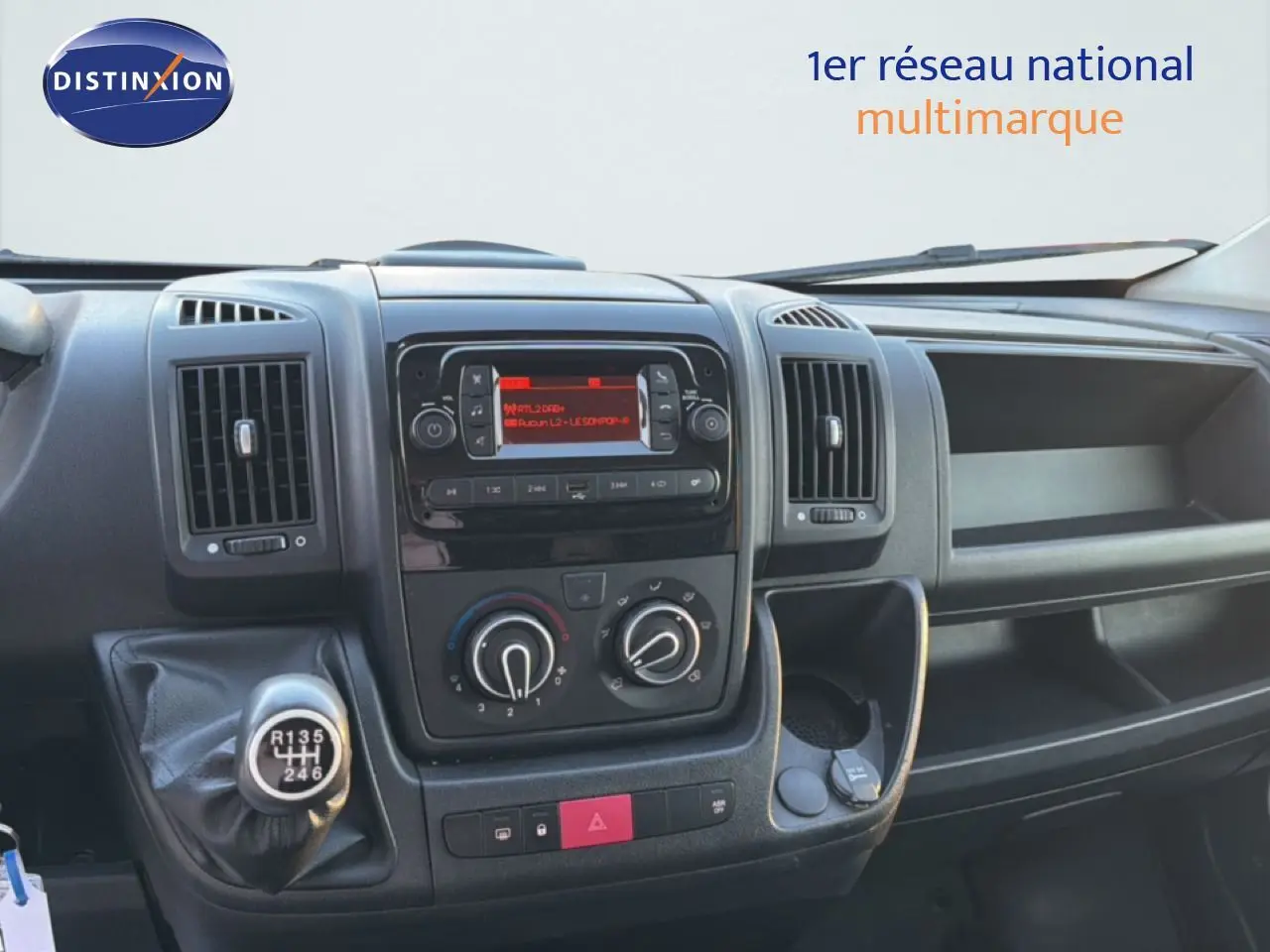 Vue intérieure du tableau de bord de l'Opel Movano Fourgon blanc, avec console centrale et levier de vitesse manuel visible.