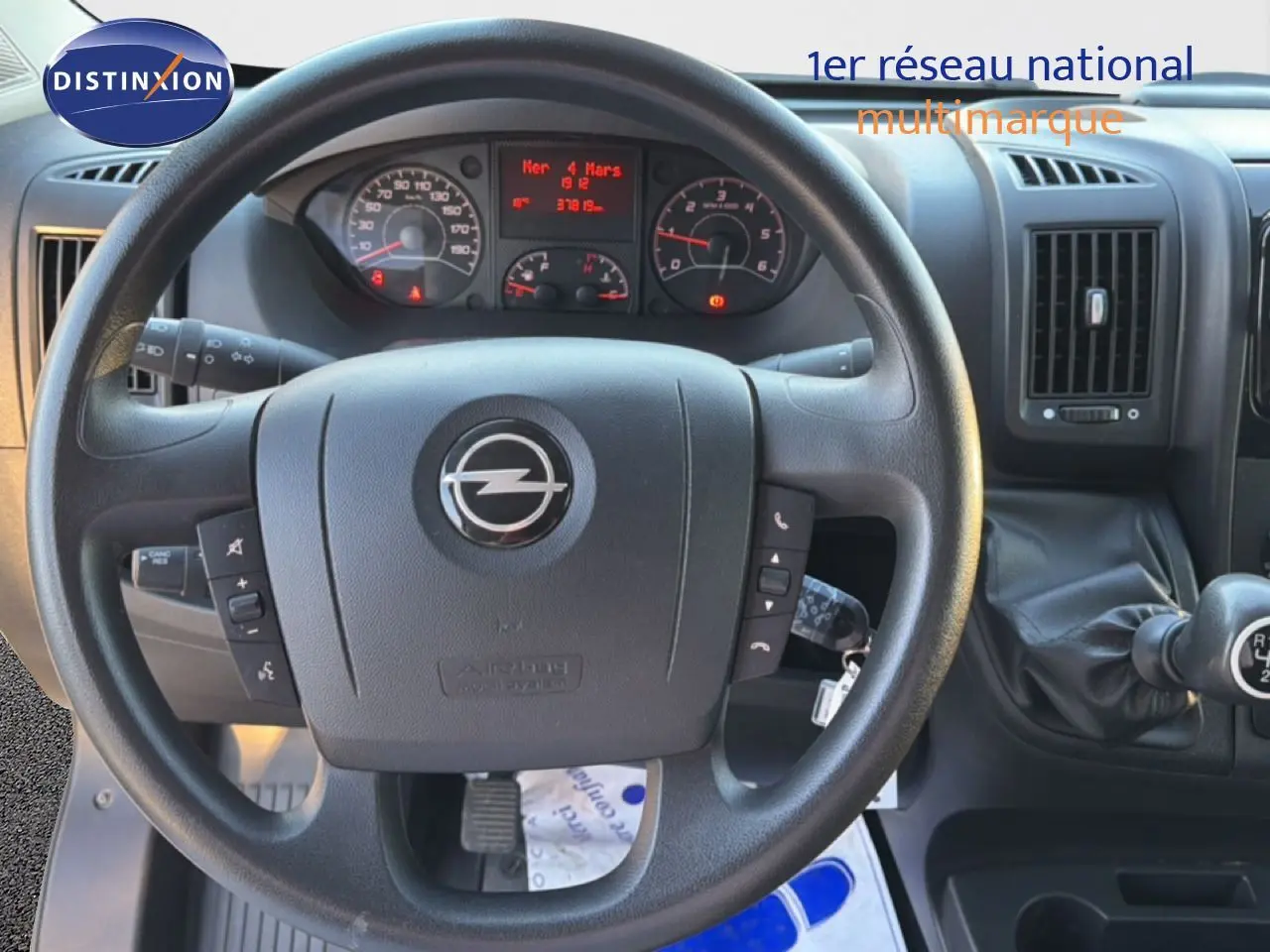 Vue rapprochée du volant noir de l'Opel Movano Fourgon 2023 avec tableau de bord et levier de vitesses manuel visible.