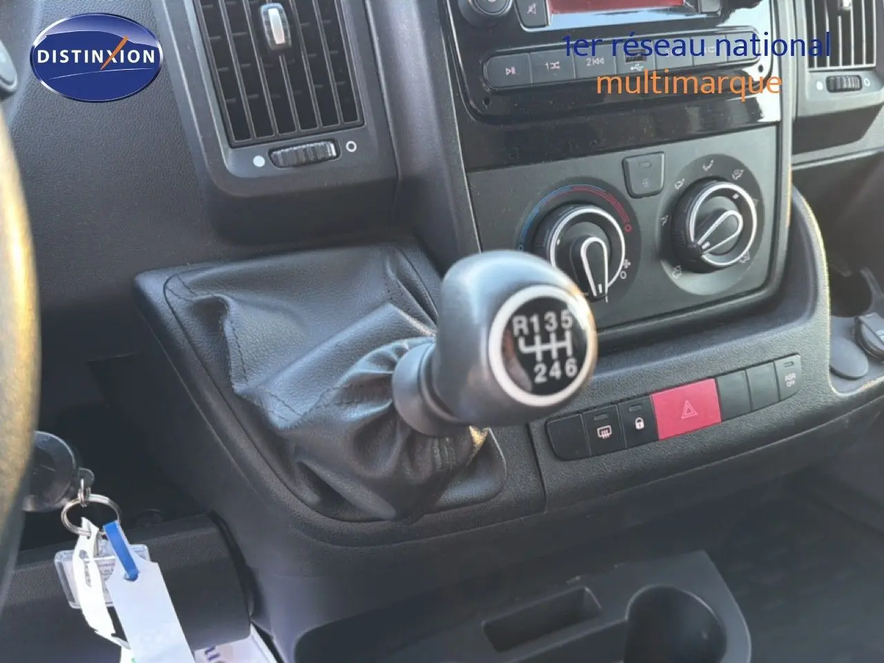 Gros plan sur la boîte manuelle et la console centrale noire de l'Opel Movano Fourgon blanc, avec commandes de climatisation visibles.