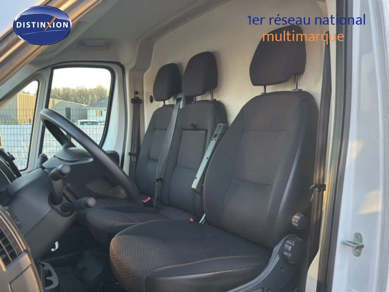 Vue intérieure côté conducteur montrant les sièges noirs du fourgon Opel Movano blanc, version L2H2 2023.