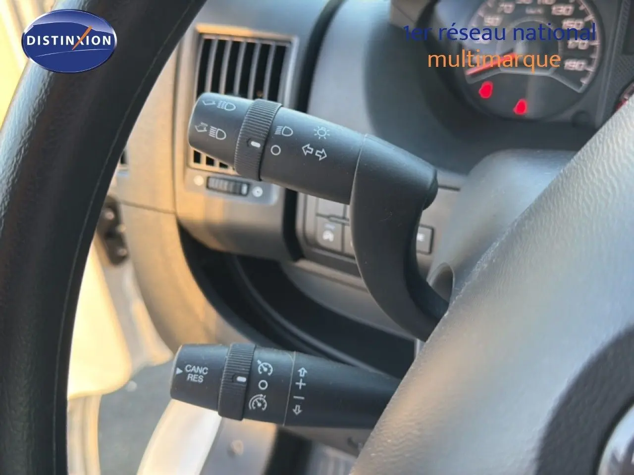 Gros plan sur les commandes de clignotants et régulateur de vitesse derrière le volant d'un Opel Movano Fourgon blanc 2023.