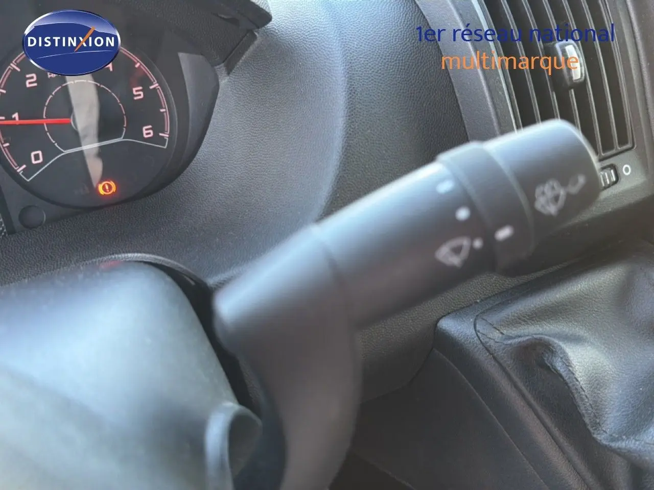 Gros plan sur la commande d’essuie-glace à gauche du volant dans l’habitacle noir d’un Opel Movano Fourgon blanc.