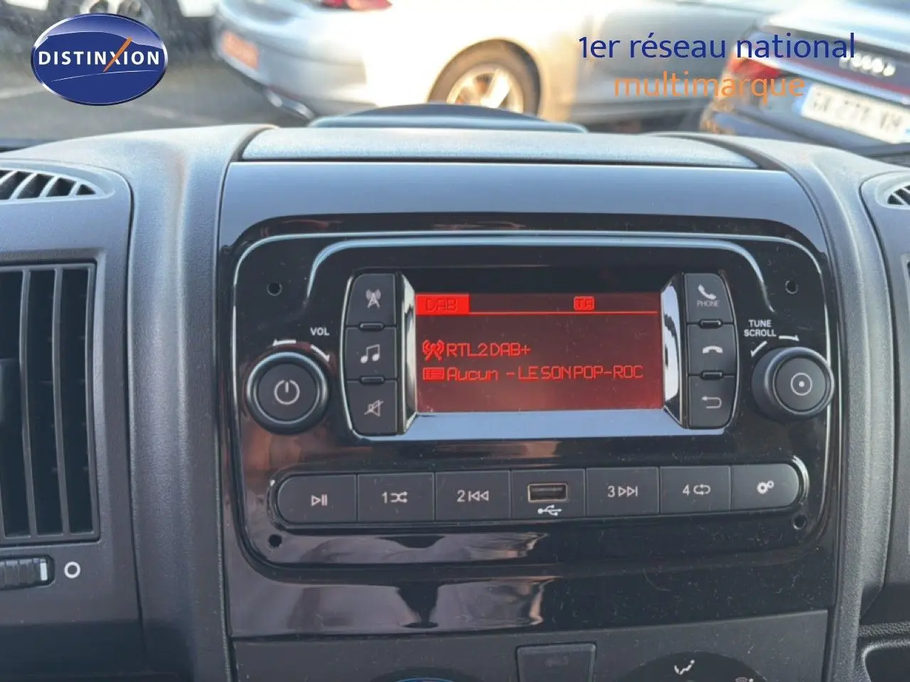 Vue rapprochée du tableau de bord noir de l’Opel Movano Fourgon 2023, avec l’écran radio affichant une station DAB+ rouge.
