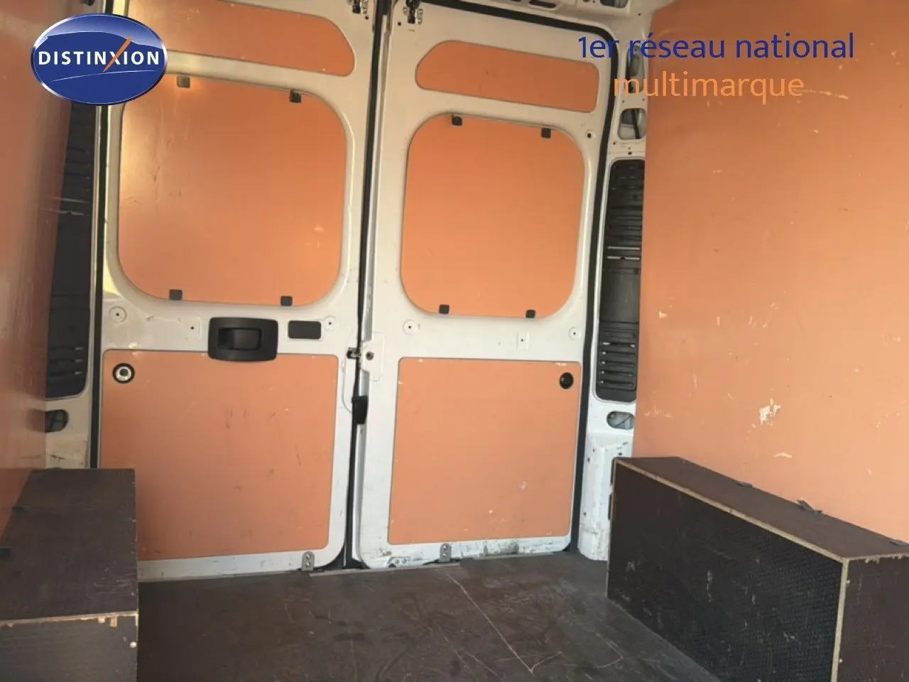 Vue intérieure arrière du fourgon blanc Opel Movano L2H2 2023, montrant les portes ouvertes et le plancher avec protections latérales.