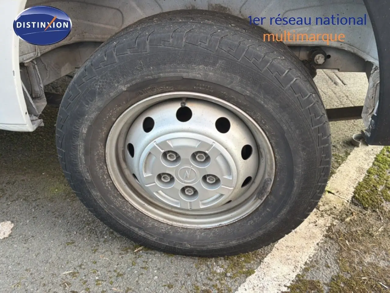 Gros plan sur la roue avant droite du fourgon blanc Opel Movano L2H2 2023 avec jante acier et logo Opel central.