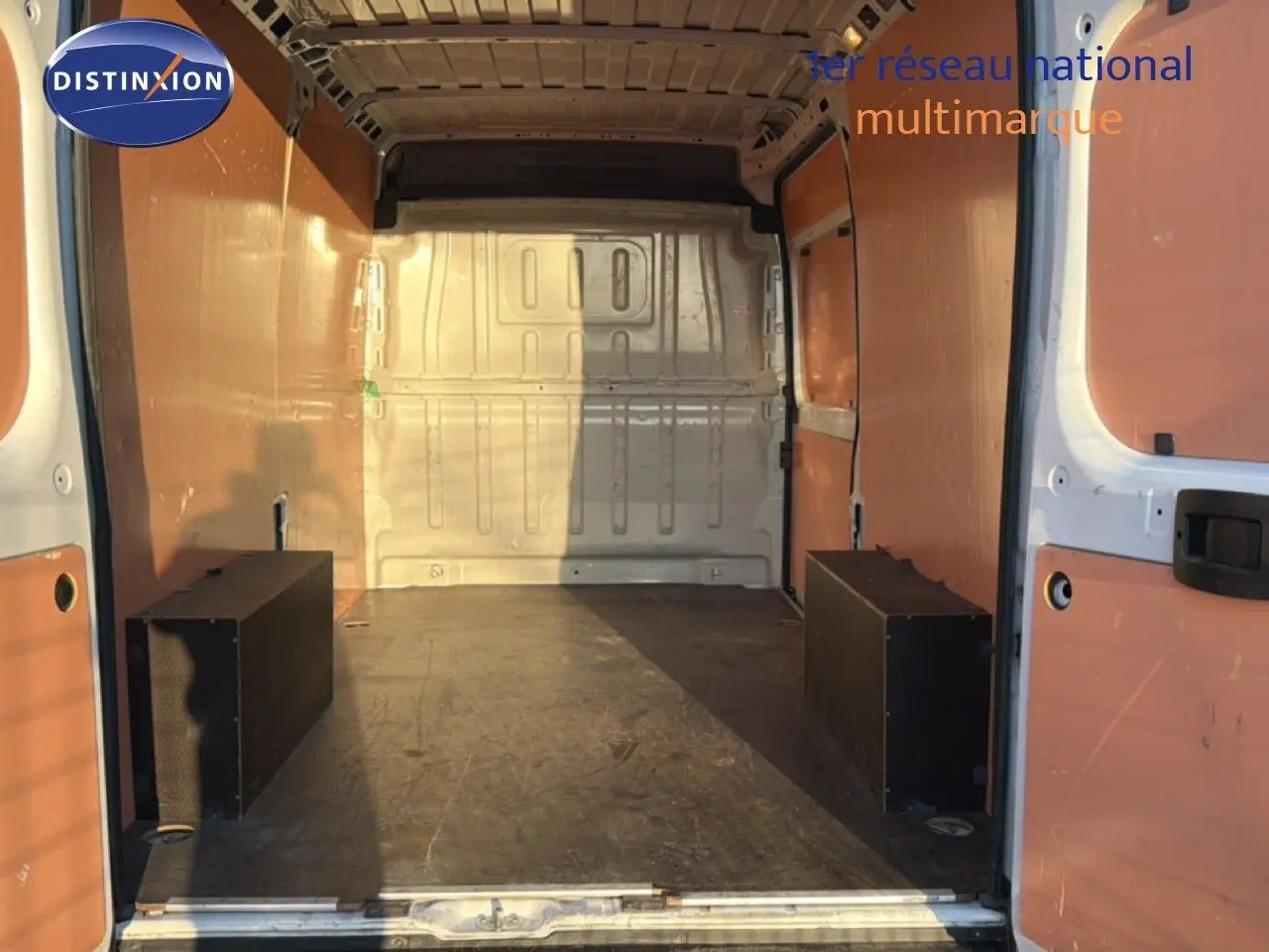 Vue intérieure arrière du fourgon Opel Movano blanc icy, montrant l'espace de chargement avec parois en bois et plancher noir.