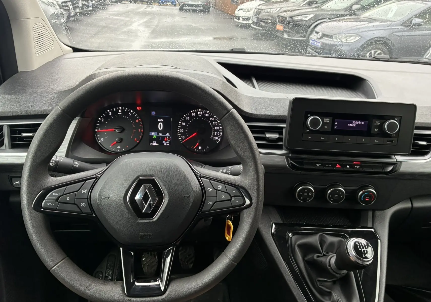 Vue intérieure centrée sur le volant noir et le tableau de bord du Renault Kangoo blanc 2024 avec boîte manuelle et écran multimédia.