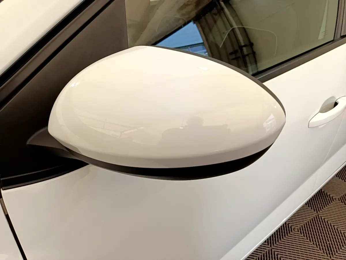 Gros plan sur le rétroviseur côté gauche blanc d'une Dacia Sandero Confort TCe 90 2022, avec porte et poignée visibles.