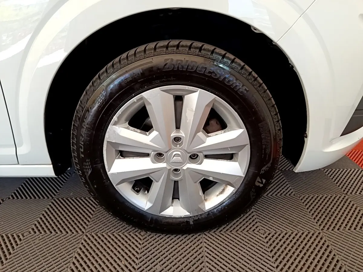 Gros plan sur la roue avant droite d’une Dacia Sandero blanche avec jante argentée et pneu Bridgestone.