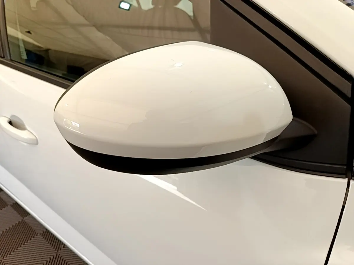 Gros plan sur le rétroviseur côté gauche blanc d'une Dacia Sandero Confort TCe 90 2022, avec porte et poignée visibles.