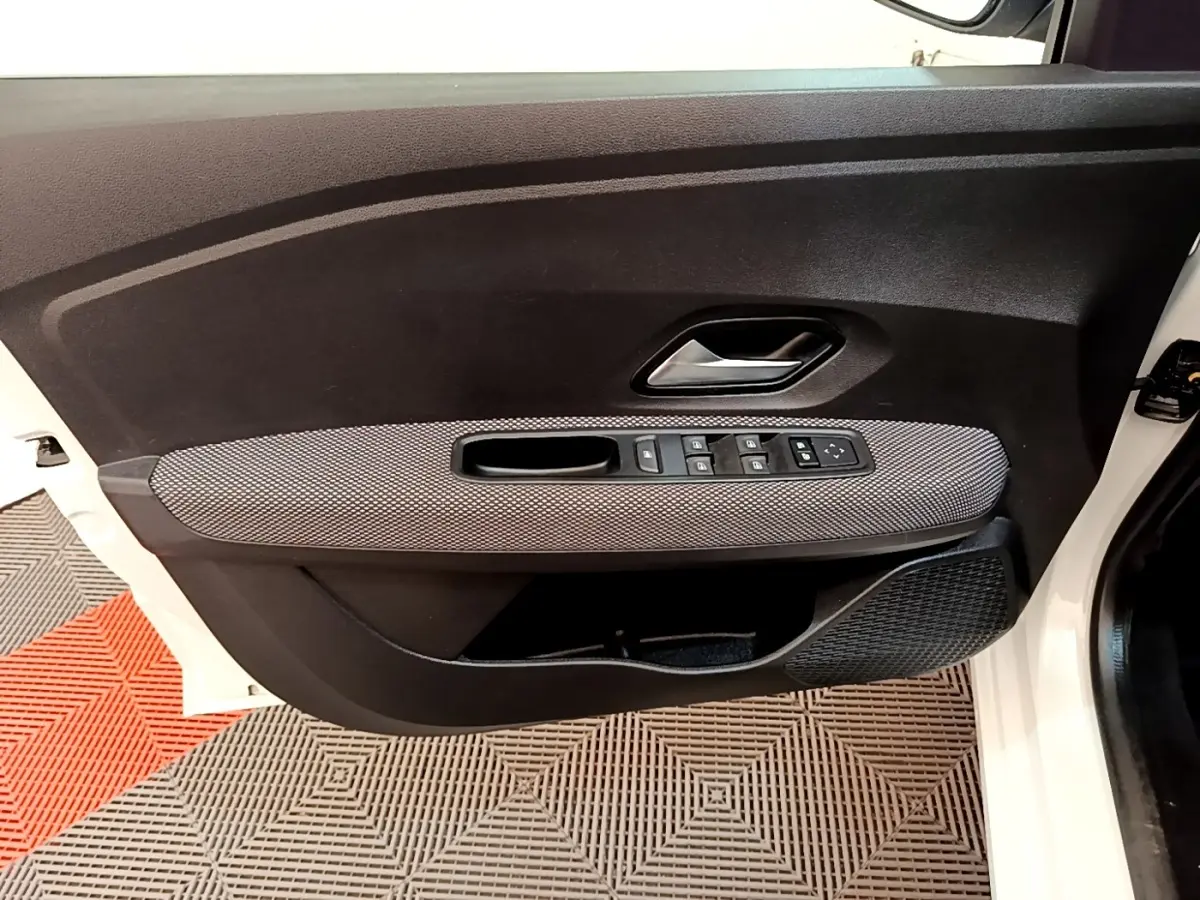 Vue intérieure de la porte avant gauche blanche de la Dacia Sandero 2022 avec commandes électriques et habillage gris.