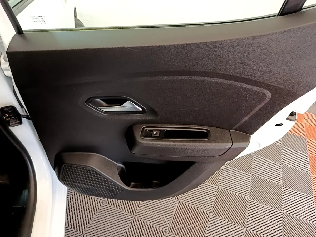 Vue rapprochée de la porte arrière droite noire intérieure d’une Dacia Sandero blanche 2022, avec poignée et commande de vitre.