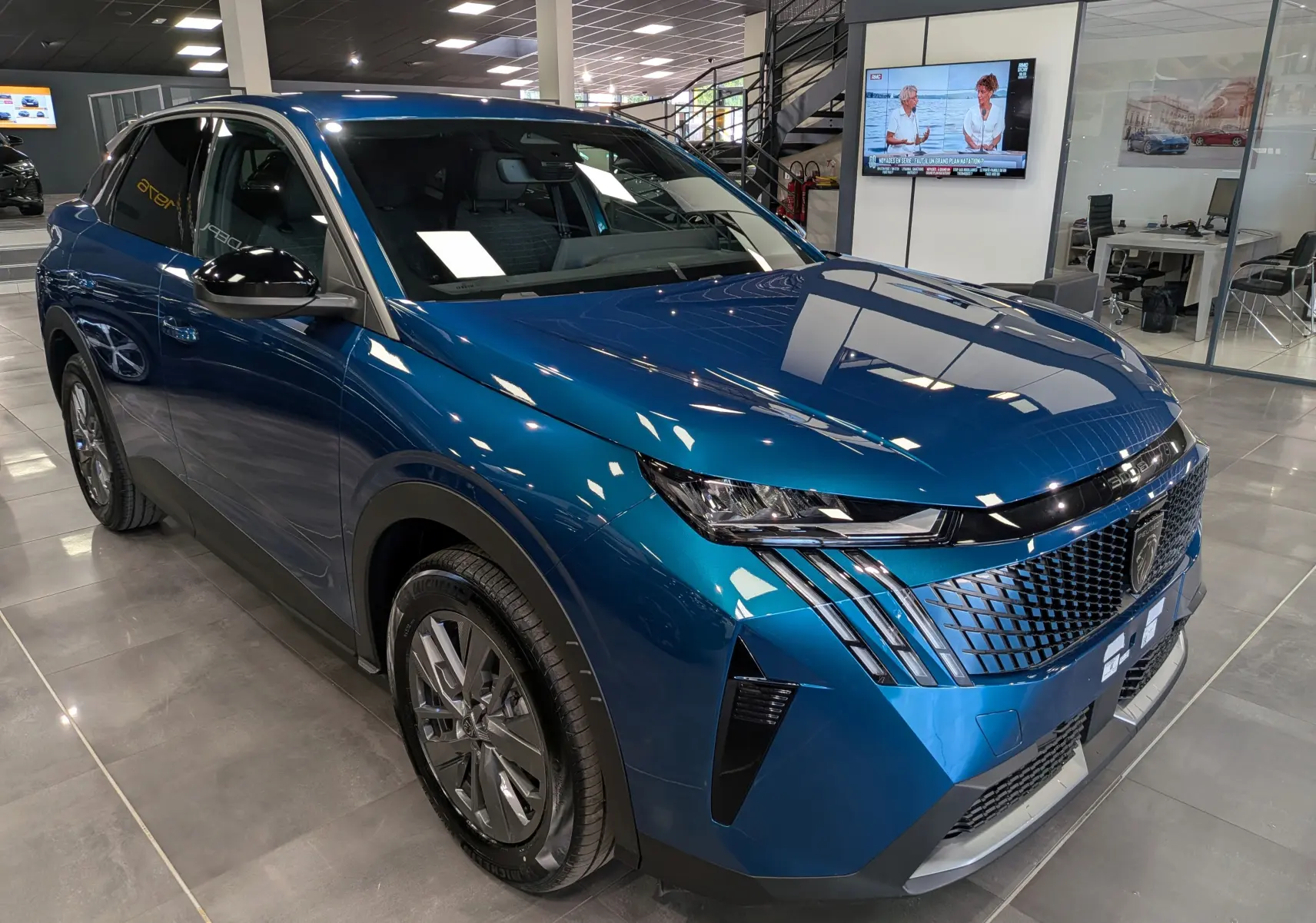 Peugeot 3008 Hybrid 145 ch en Bleu Obsession, vue 3/4 avant droit en intérieur avec calandre distinctive et phares LED.