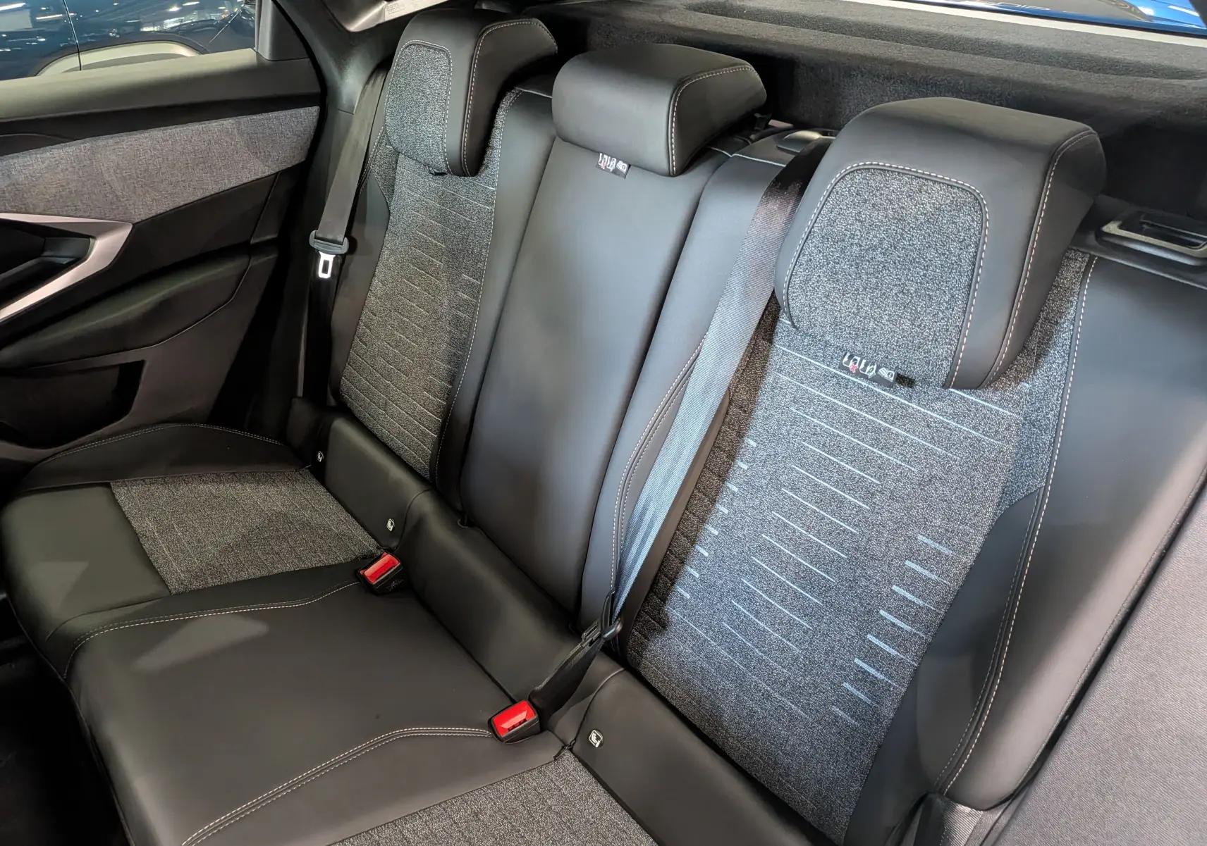 Vue intérieure arrière du Peugeot 3008 Hybrid 145 en Bleu Obsession, montrant les sièges mixtes cuir et tissu gris.