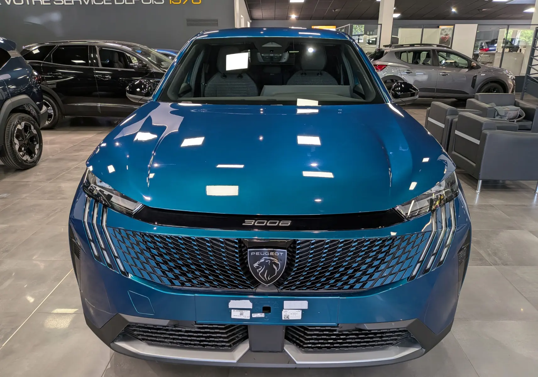 Vue de face du Peugeot 3008 Hybrid bleu Obsession en showroom, mettant en valeur sa calandre et son logo lion distinctifs.