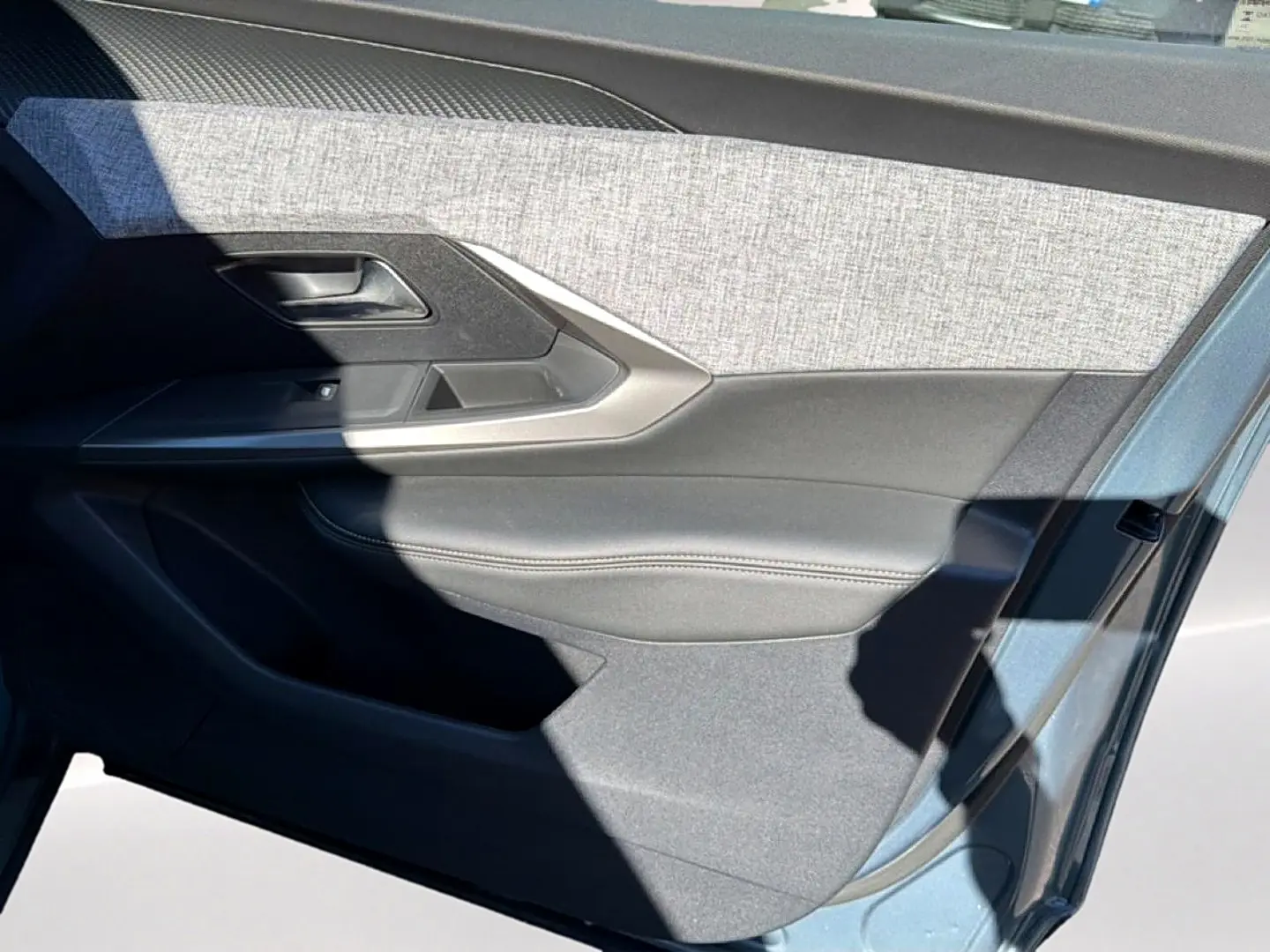 Vue rapprochée de la porte avant gauche du Peugeot 3008 2025 bleu ingaro, avec habillage tissu et cuir gris.