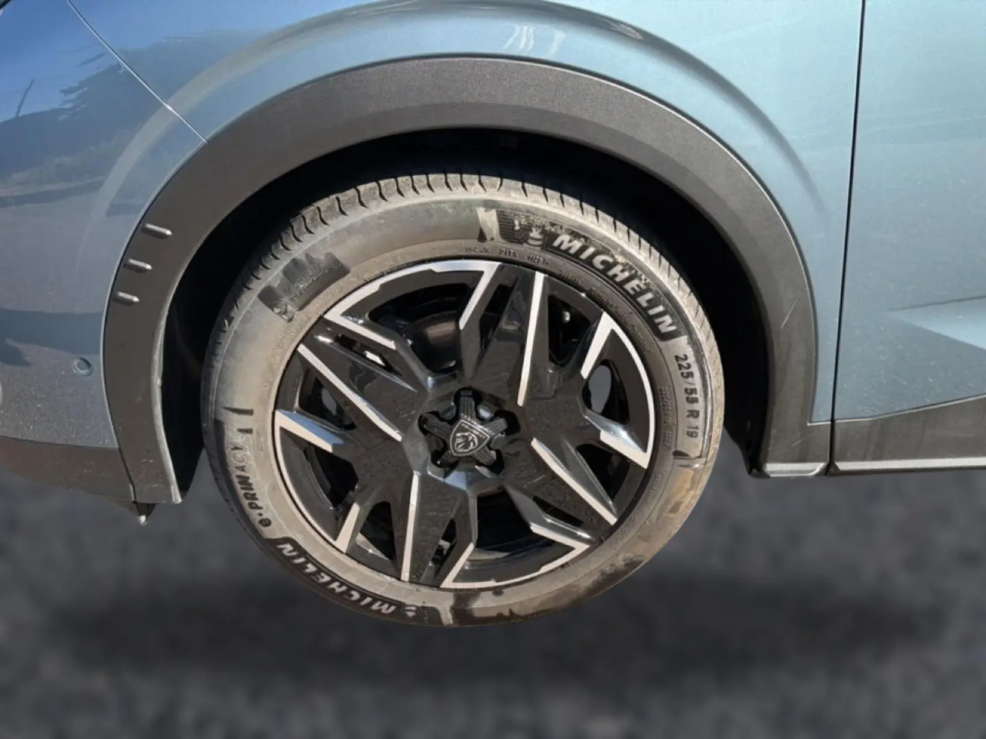 Gros plan sur la roue arrière droite du Peugeot 3008 bleu 2025 avec jante alu noire et détails Michelin visibles.