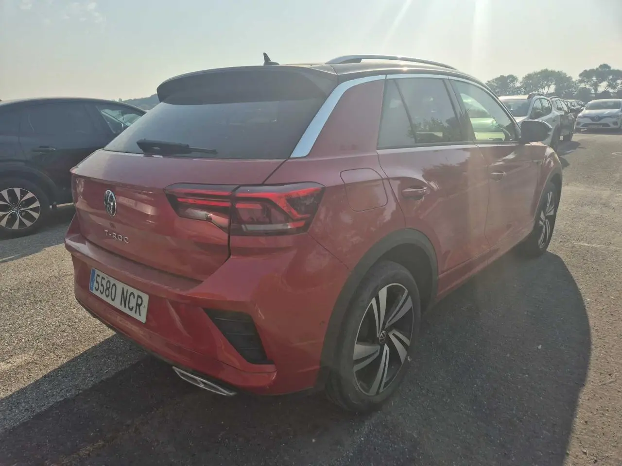 Volkswagen T-Roc rouge métal foncé vue 3/4 arrière droit avec toit panoramique et jantes R-Line.