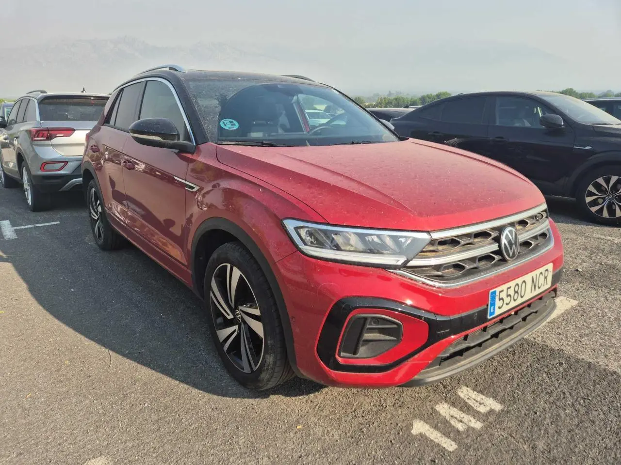 Volkswagen T-Roc rouge métal foncé vue 3/4 avant droit avec toit noir et jantes alliage.