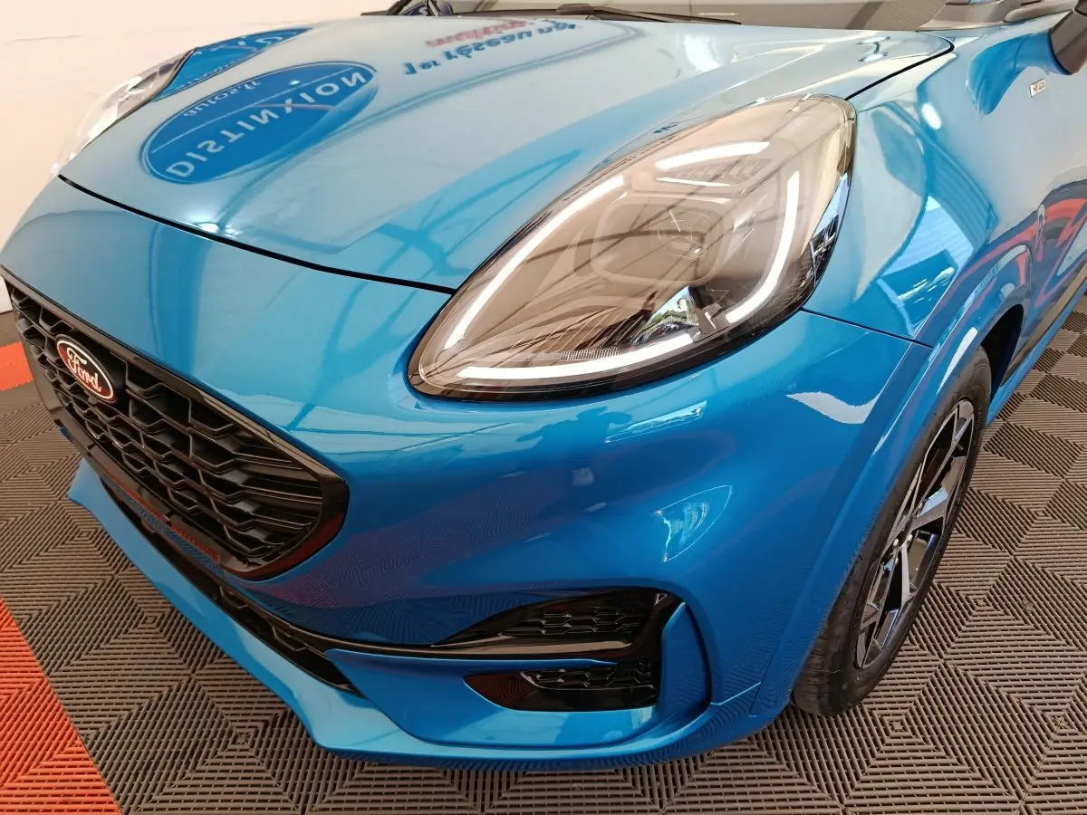 Vue 3/4 avant droit d'une Ford Puma bleu vif mettant en valeur son phare LED et sa calandre noire sportive.