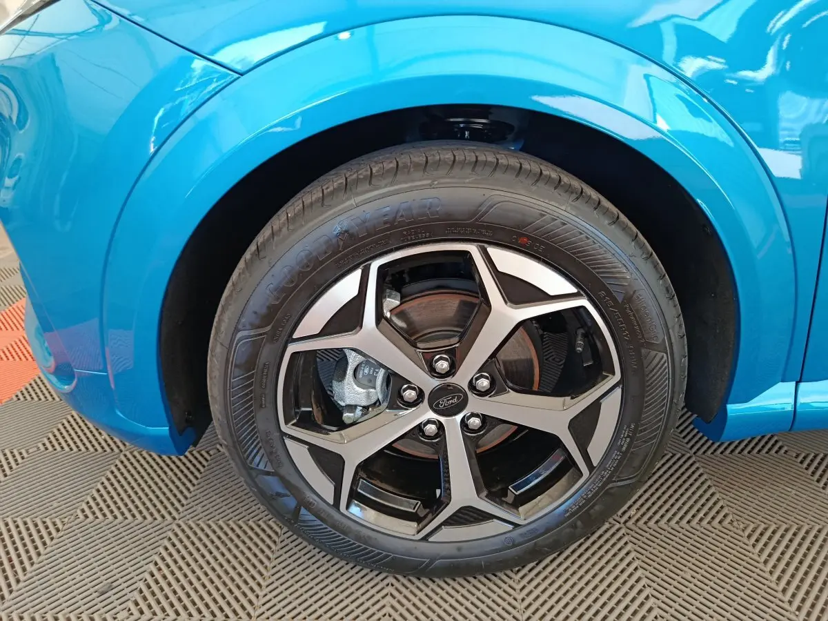 Gros plan sur la roue avant droite du Ford Puma bleu 2025 avec jante alliage noire et argentée design étoile.