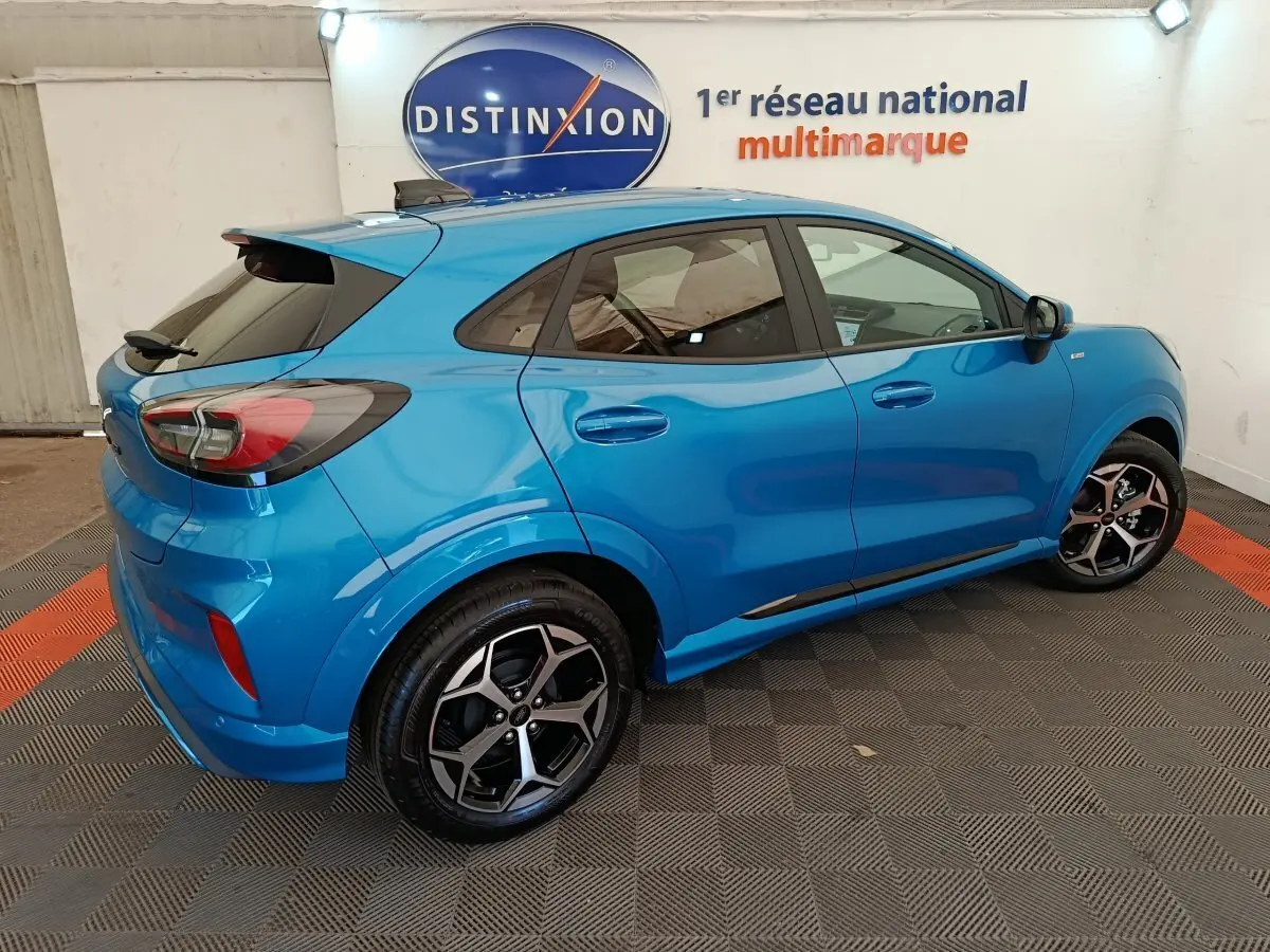 Vue 3/4 arrière droite d'un Ford Puma bleu 2025 finition ST-LINE avec jantes alliage et vitres teintées.
